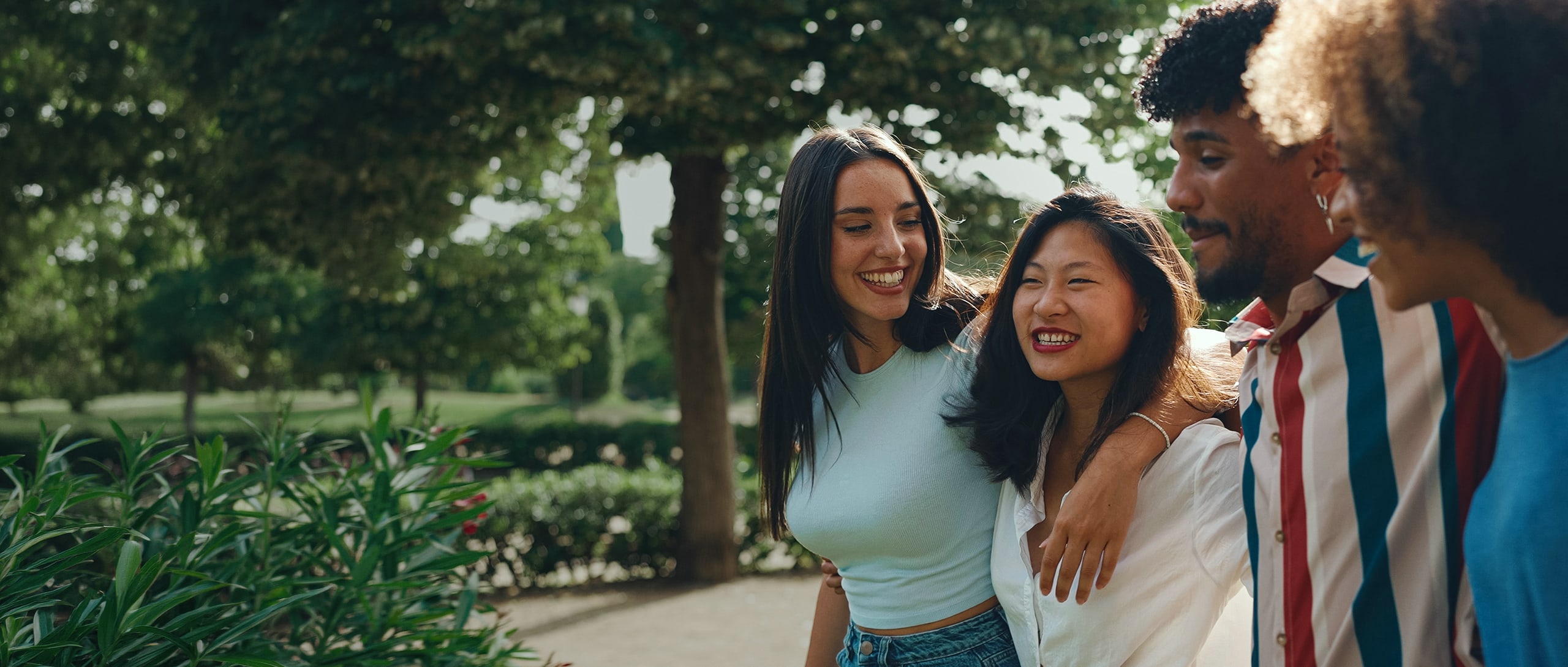 A group of friends wearing blue, smiling and laughing as they walk with their arms around one another.