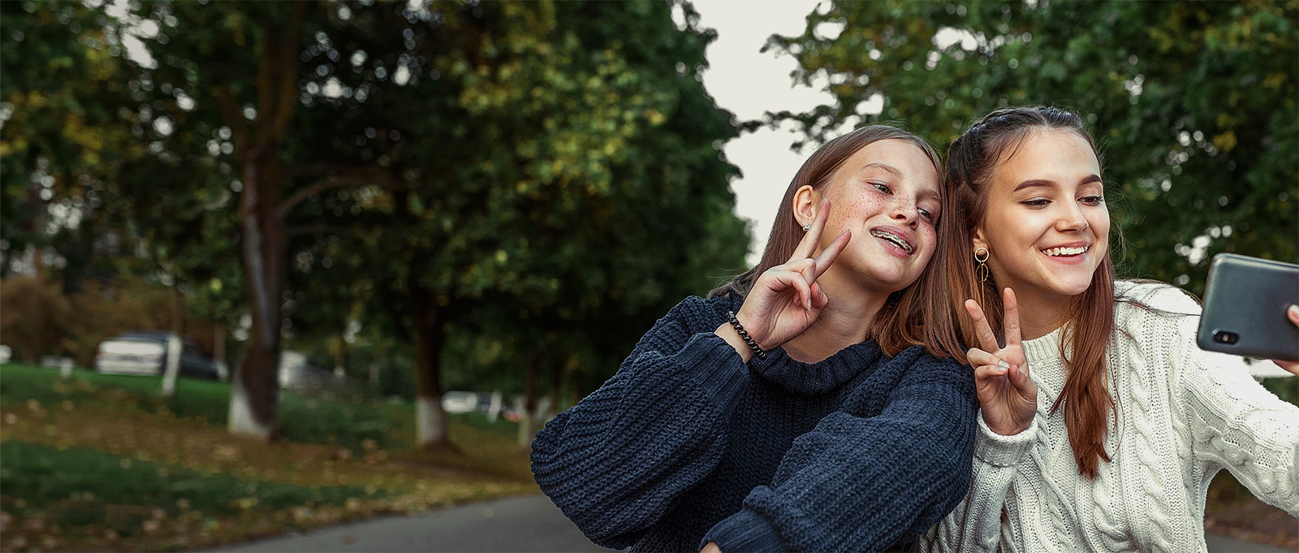 Two young girls posing for a photo and showing off their braces