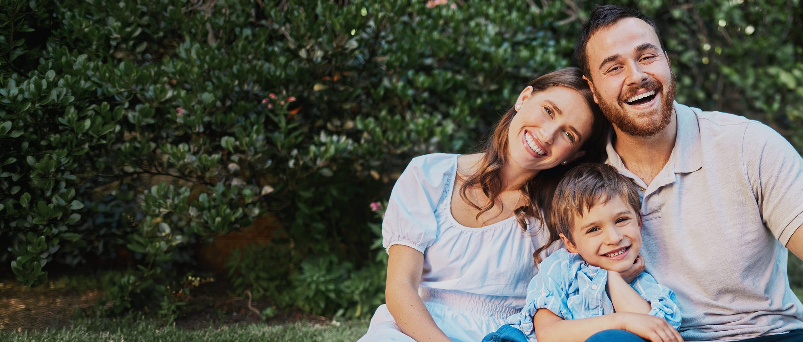 A young family wearing blue smiles together.