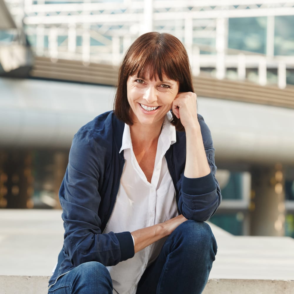 A woman is crouched down. She has her elbows on her knees and her head is resting on one of her fists.