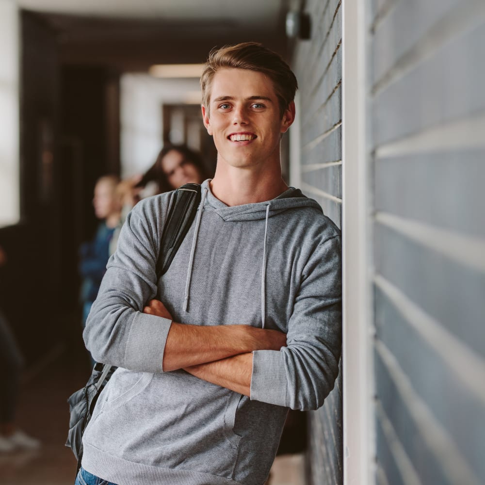A young man wearing a grey sweater is smiling.