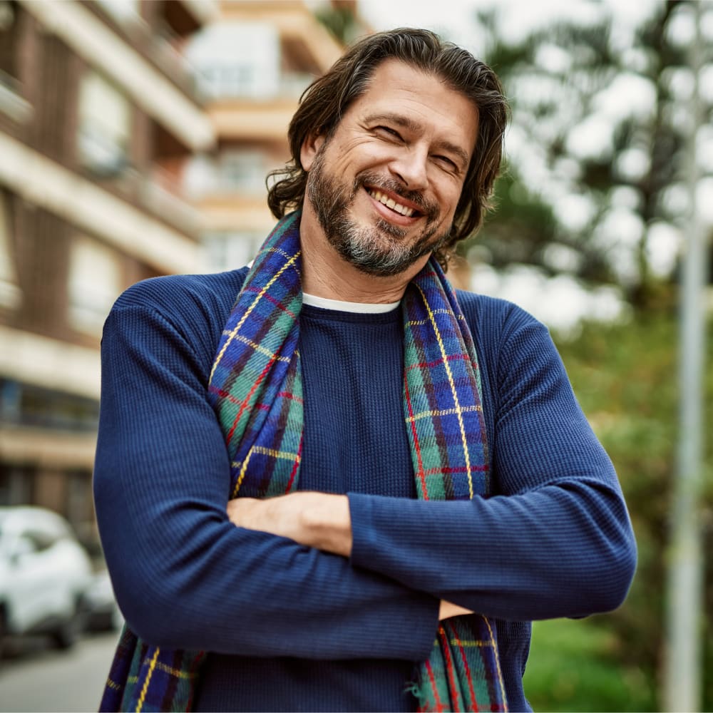 A man in a blue shirt and scarf is smiling