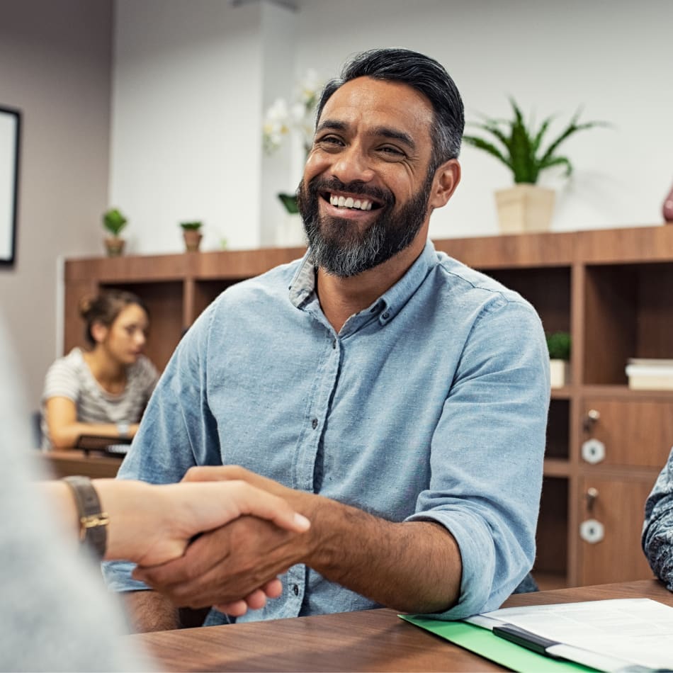 A man is smiling and shaking someone's hand.