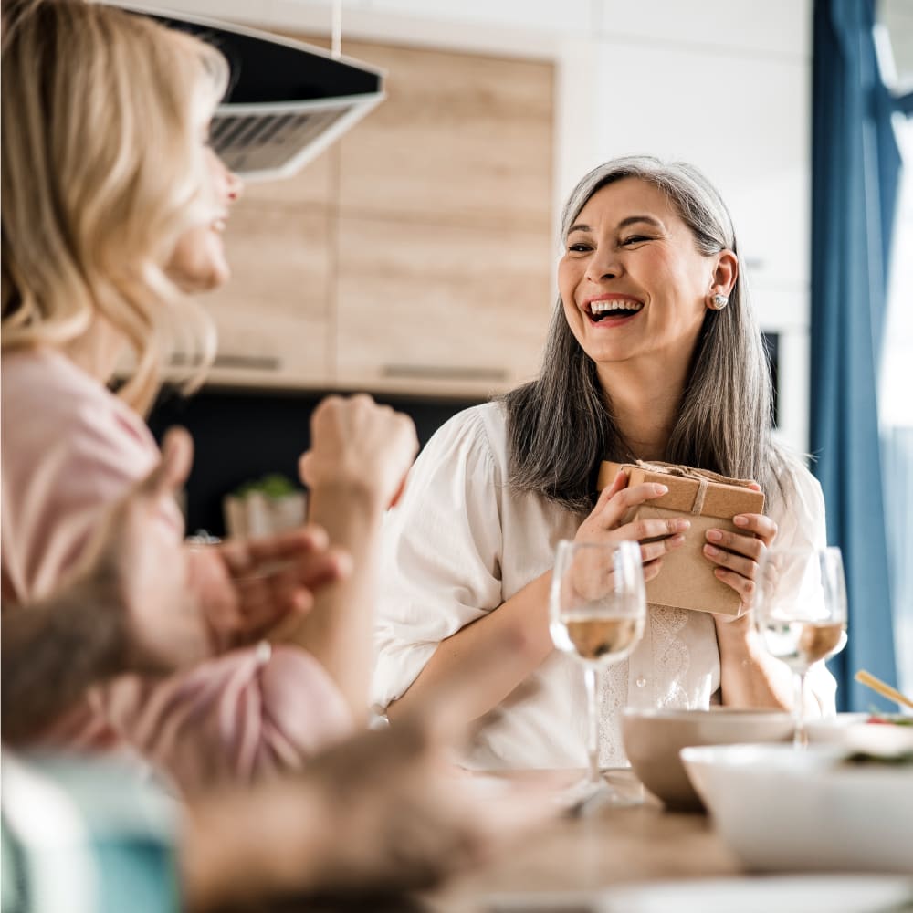 Two women are sitting at lunch chatting and smiling.