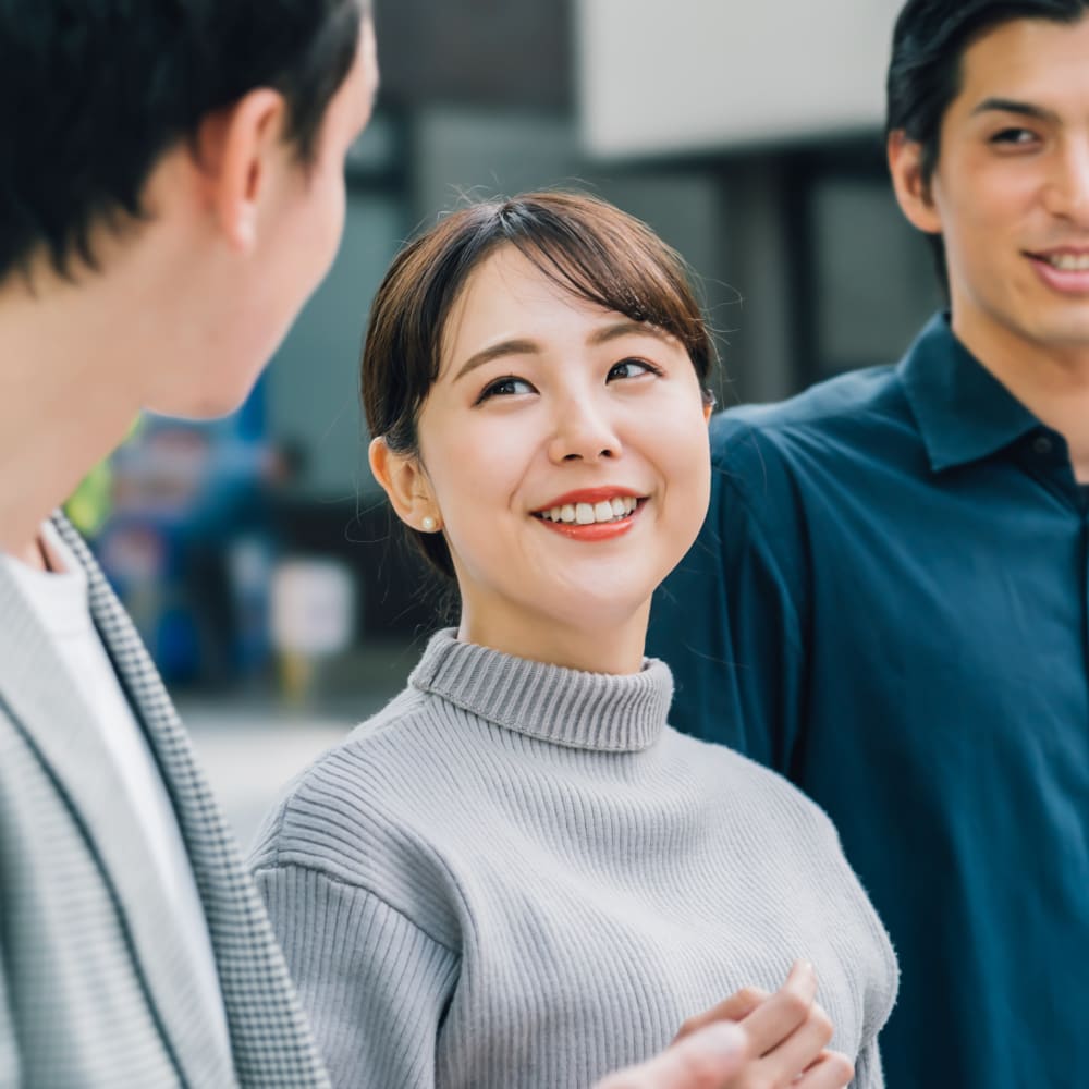 A woman is smiling and walking with two men.