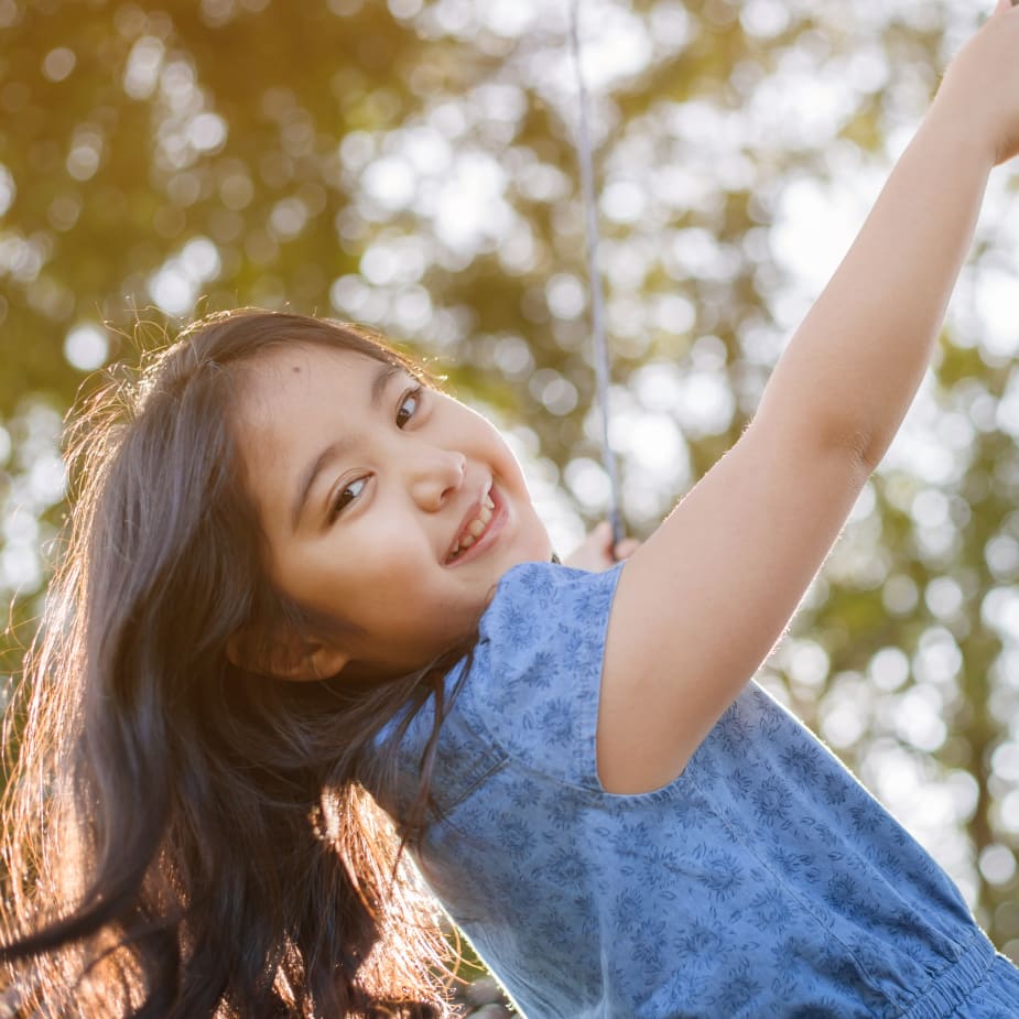 A young girl is playing with a swing.