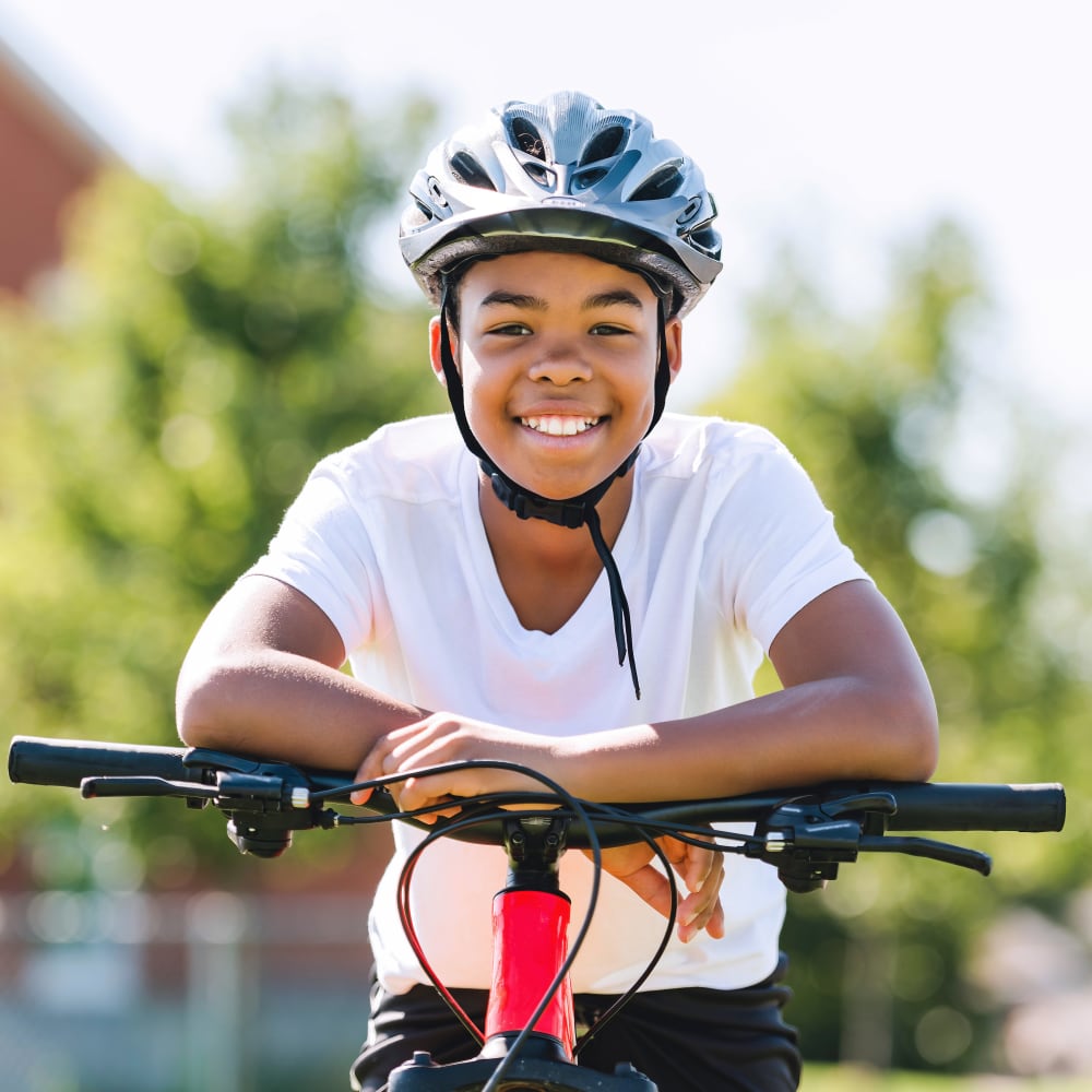 A young boy is smiling while sitting on his bike.