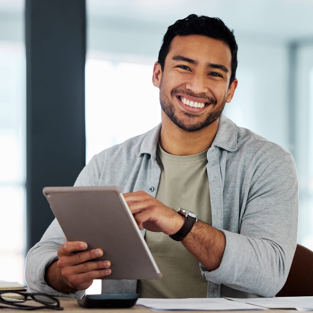A man is smiling and using a tablet.