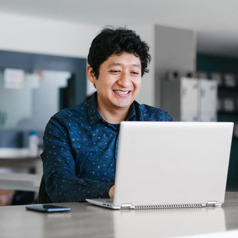 A man is smiling while using his laptop.