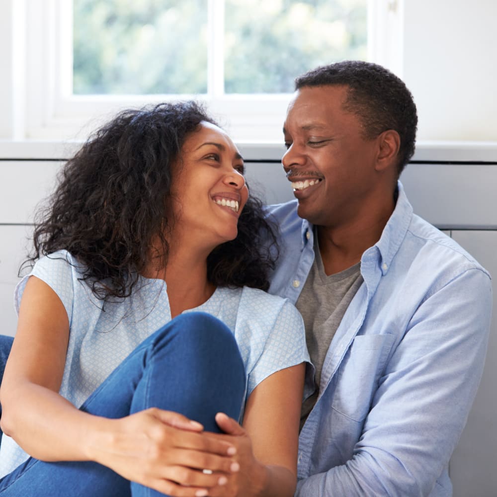 A man and a woman are sitting together looking at each other and smiling.